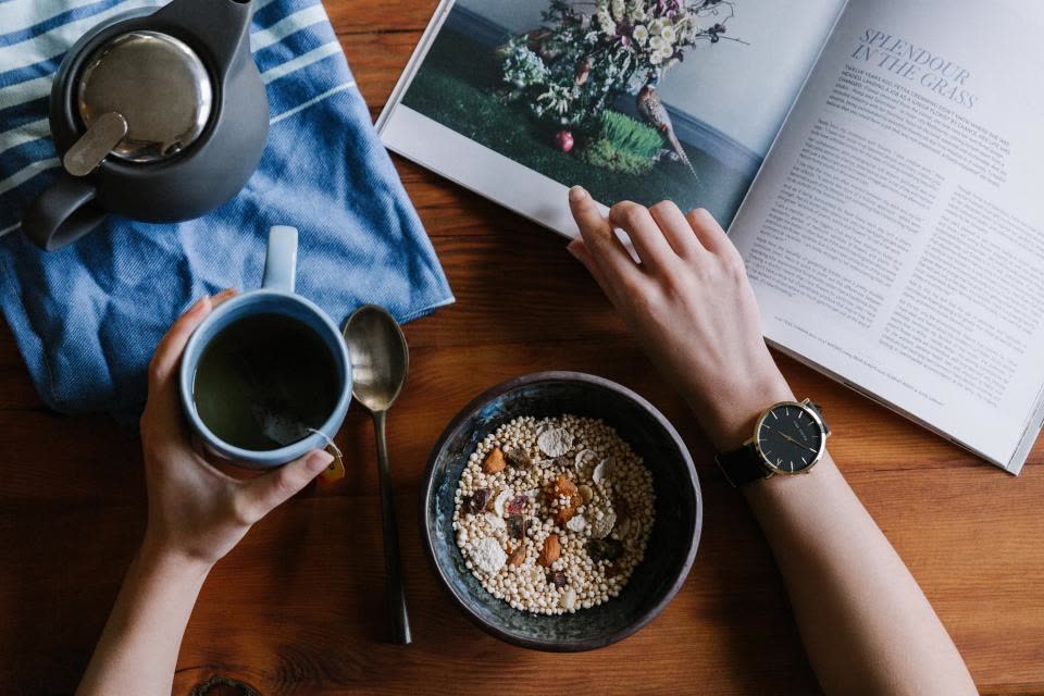 Café da manhã com granola, chá e um livro aberto sobre a mesa