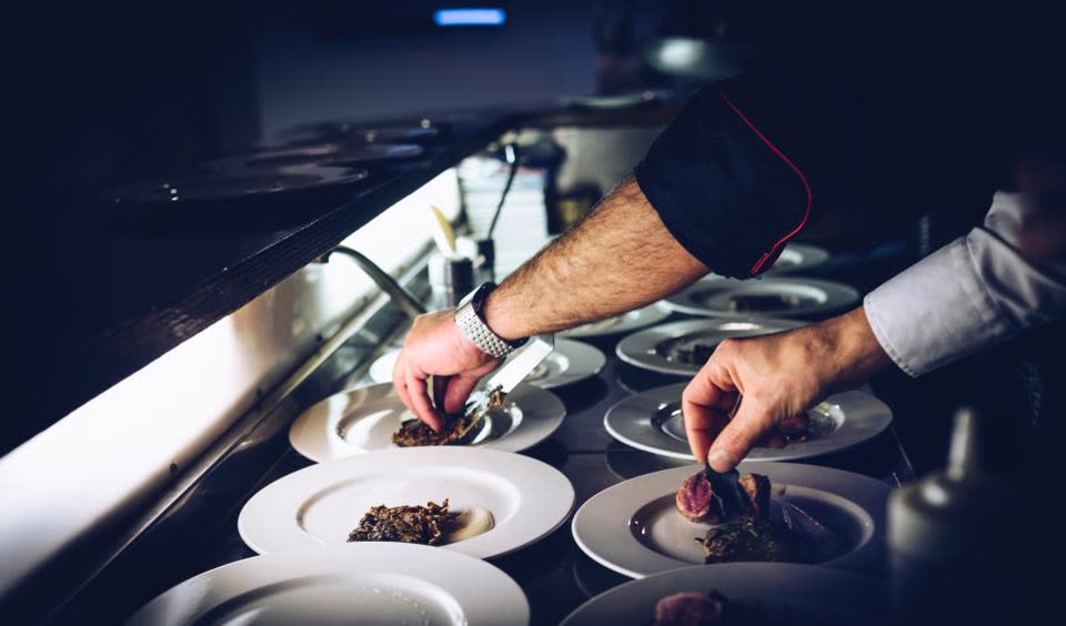 Chef finalizando pratos no passe da cozinha